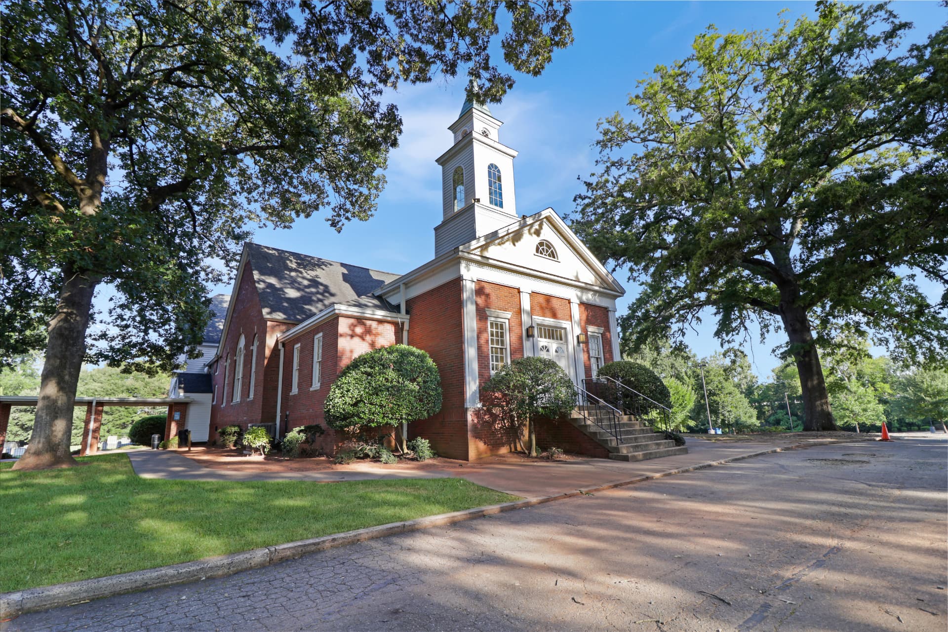Ground-level view of the brick chapel with steeple and mature oaks